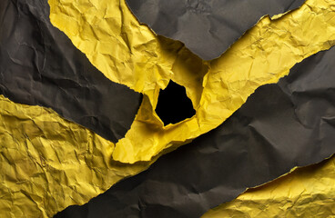 Stacked yellow and black wrinkled or crumpled paper with a hole in the middle forms an unusual background.