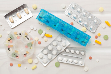 Daily pill organizer with medications on wooden background, top view