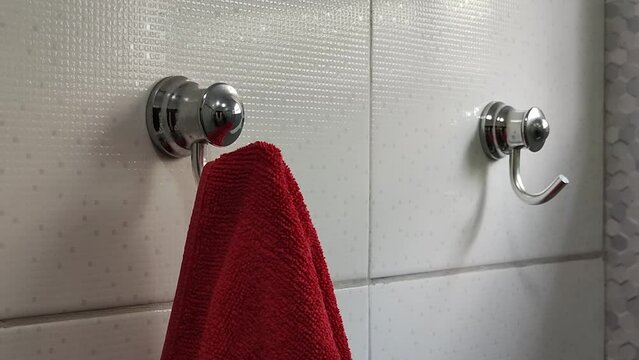 Close-up of a towel rack in the bathroom. man hangs a red towel on the hook of the hanger, close-up