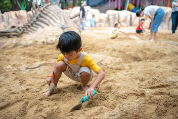 Asian kid boy 5 year old enjoying play outdoor sandbox having fun on playground in sandpit.