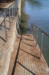 Concrete ramp with a fence leading down to the ocean sea water