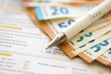 Filling italian tax form process with pen and euro money bills close up. Tax paying period and...