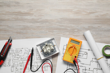 Wiring diagrams and digital multimeter on white wooden table, flat lay. Space for text