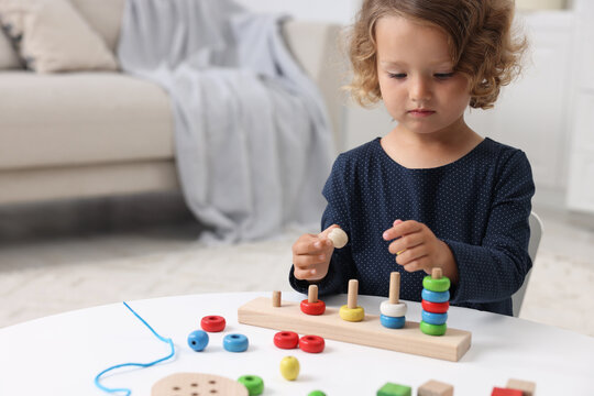 Motor skills development. Little girl playing with stacking and counting game at table indoors