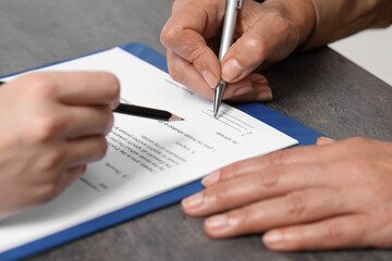 Manager showing client where she must to mark signature at dark table, closeup