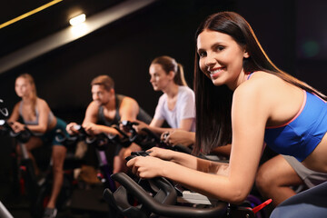 Fototapeta na wymiar Group of people training on exercise bikes in fitness club
