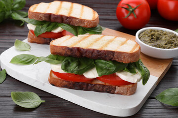 Delicious Caprese sandwiches with mozzarella, tomatoes and basil on wooden table