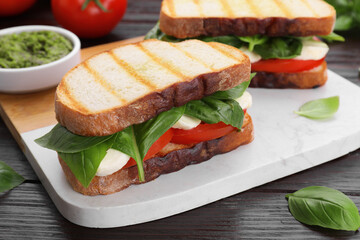 Delicious Caprese sandwiches with mozzarella, tomatoes and basil on wooden table, closeup
