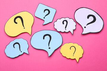 Different paper speech bubbles with question marks on pink background, flat lay