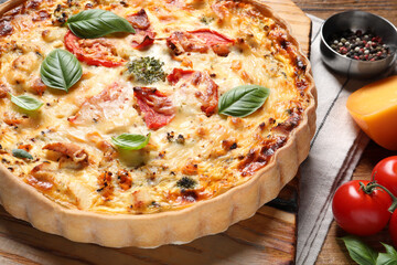 Tasty quiche with tomatoes, basil and cheese served on wooden table, closeup