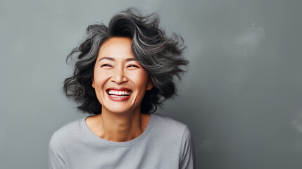 portrait of a happy smiley asian older lady grey background isolated
