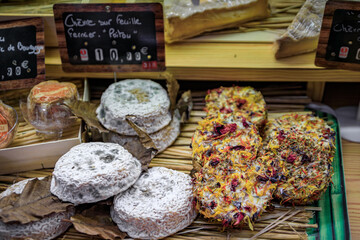 Mature Poitou goat cheese and goat cheese rounds coated with dried flowers at an artisanal cheese shop in the old town Vieil Antibes, South of France