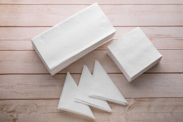Clean paper towels and tissues on light wooden table, flat lay