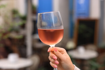Woman holding glass of rose wine outdoors, closeup