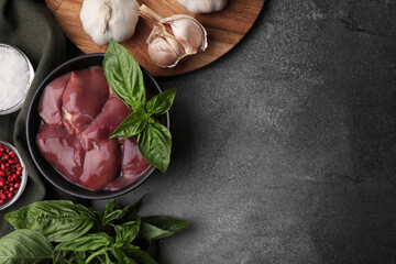 Bowl of raw chicken liver with basil and products on grey table, flat lay. Space for text