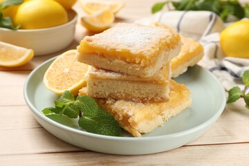 Fototapeta na wymiar Tasty lemon bars with powdered sugar and mint on wooden table, closeup