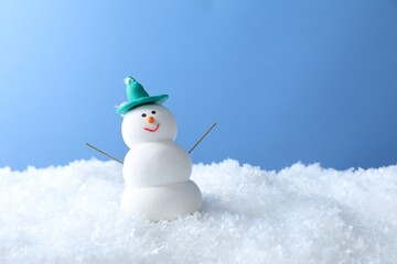 Funny snowman on snow against light blue background, space for text