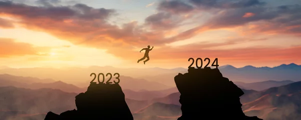 Keuken spatwand met foto silhouette of a man jumping from one mountain to another leaving the year 2023 behind and reaching the new year 2024 - concept of setting goals for the next year © Jess rodriguez