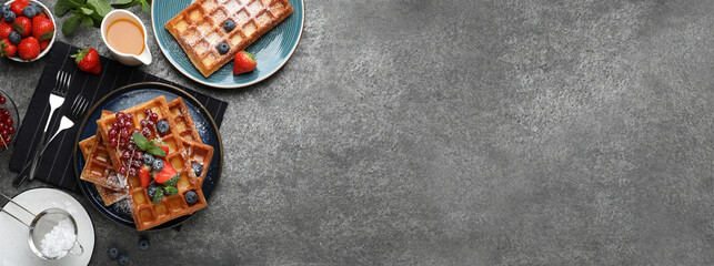 Delicious Belgian waffles with fresh berries served on grey table, flat lay. Banner design with...