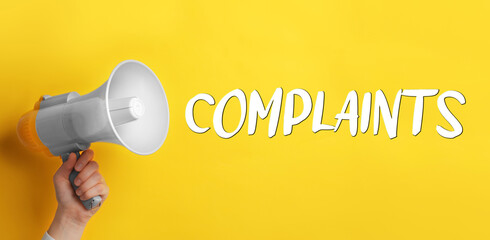 Man holding megaphone on yellow background, closeup. Word Complaints coming out from device. Banner...