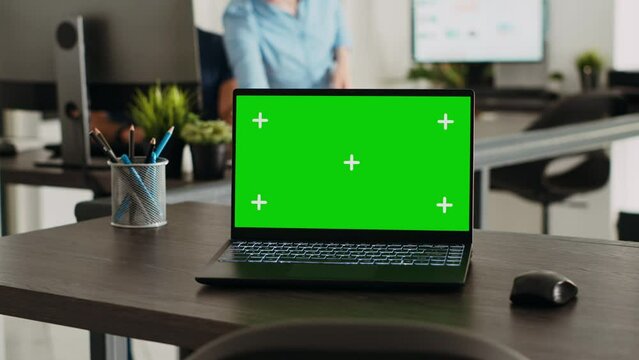 Wireless pc with greenscreen at empty desk in creative agency workplace, laptop showing blank copyspace on display. People working on startup business, workstation with mockup template.