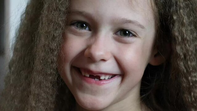 Cute little girl smiles and shows her fallen front milk teeth. Teeth growth. Close-up. Portrait of a 6-year-old rebec