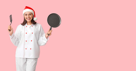Beautiful female chef in Santa hat, with frying pan and spatula on pink background with space for text