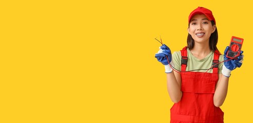 Asian female electrician holding tester on yellow background with space for text