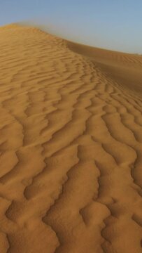 Sand blowing over sand dunes in wind, Sahara desert. Vertical video