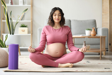 Sporty pregnant woman meditating at home