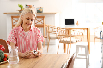 Mature diabetic woman measuring blood sugar level with glucometer in kitchen