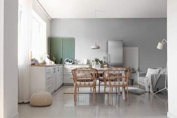 Interior of light kitchen with stylish fridge, counters, sofa, table and chairs
