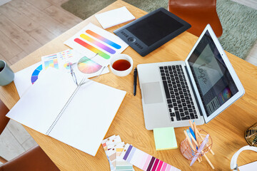 Graphic designer's workplace with laptop and color palettes in office