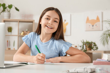 Naklejka premium Little girl doing lessons at home