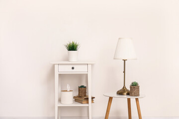 Lamp and dressing table with houseplant near white wall