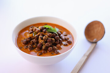 Bowl of delicious Kadala curry or chana masala curry or chick pea curry in white bowl with white background. Kerala breakfast side dish for appam puttu rice. kala chana desi chana whole bengal gram