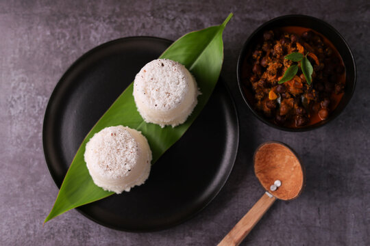 Popular South Indian breakfast puttu / pittu made of rice flour and coconut with banana and kadala curry, Kerala breakfast, India. Bamboo puttu prepared in steam