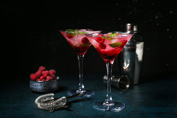 Glasses of fresh raspberry mojito and bowl with berries on blue table