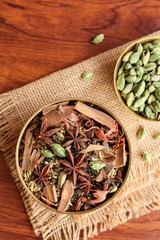 Indian spices for Indian cooking Masala for hot and spicy curry , whole spices turmeric, cardamom, black pepper in wooden spoon, star anise , paprika in Indian spice box Kerala India Sri Lanka.