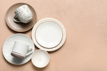 Set of stylish clean dinnerware on beige background