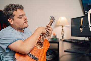 Musician preparing guitar for a live streaming from home - Powered by Adobe