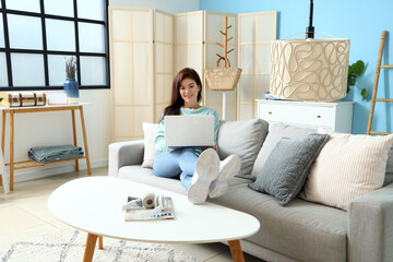 Young woman using laptop on sofa in living room