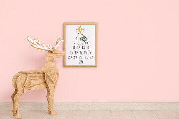 Wooden reindeer and Christmas calendar on pink wall in room