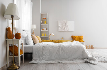 Interior of light bedroom with pumpkins and lamps