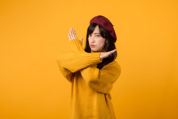 Young Asian woman in her 30s, wearing a yellow sweater and red beret, uses hand gestures to convey...