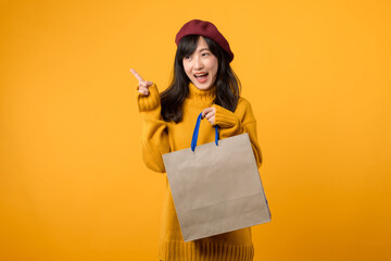 Young Asian woman in her 30s, wearing a yellow sweater and red beret, indulges in a shopping...