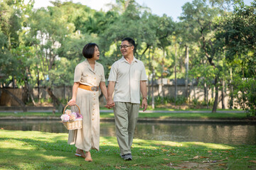 Fototapeta premium Happy Asian senior couples are enjoying talking and holding hands while strolling around the park.