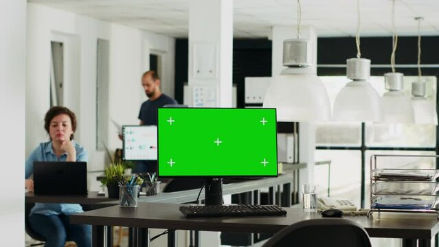 Workstation displaying greenscreen layout with copyspace on monitor at empty desk in urban coworking space. Chromakey display equipment adopted in smaller company operations. Tripod shot.