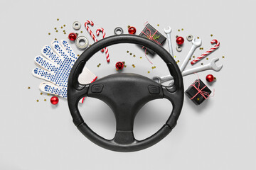 Composition with steering wheel, tools and Christmas decorations on light background