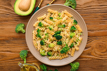 Plate of tasty pasta with broccoli on wooden background